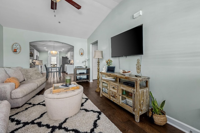 living area with arched walkways, lofted ceiling, a ceiling fan, dark wood finished floors, and baseboards