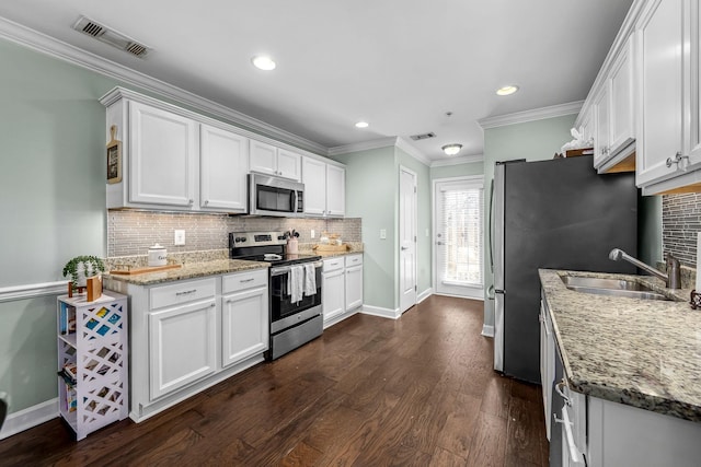 kitchen with stainless steel appliances, a sink, tasteful backsplash, dark wood-style flooring, and white cabinetry