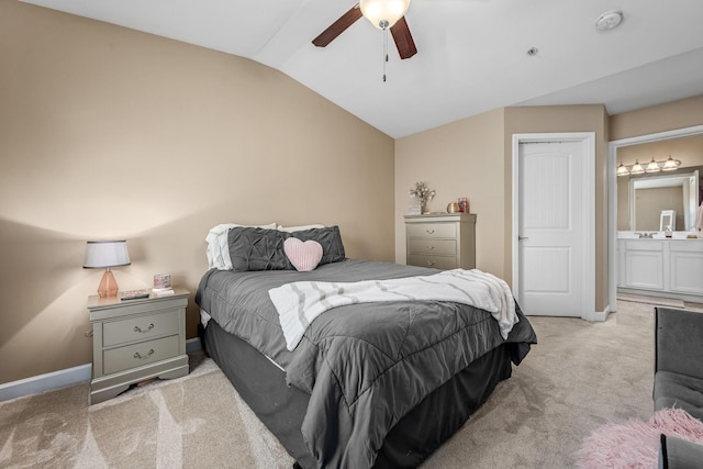 bedroom with vaulted ceiling, light carpet, baseboards, a ceiling fan, and ensuite bath