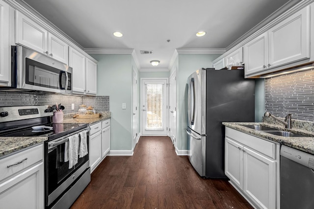 kitchen with appliances with stainless steel finishes, a sink, backsplash, white cabinets, and recessed lighting