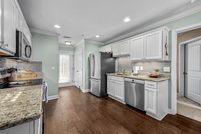 kitchen with appliances with stainless steel finishes, white cabinets, tasteful backsplash, recessed lighting, and a sink