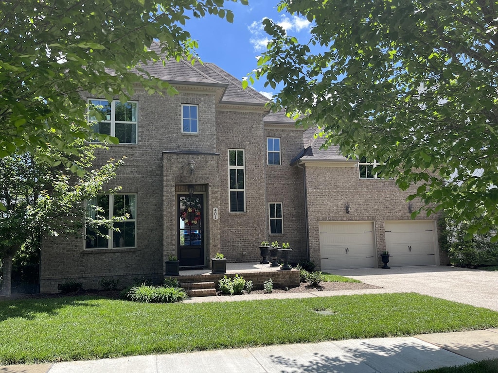 traditional home featuring a front lawn, concrete driveway, brick siding, and an attached garage