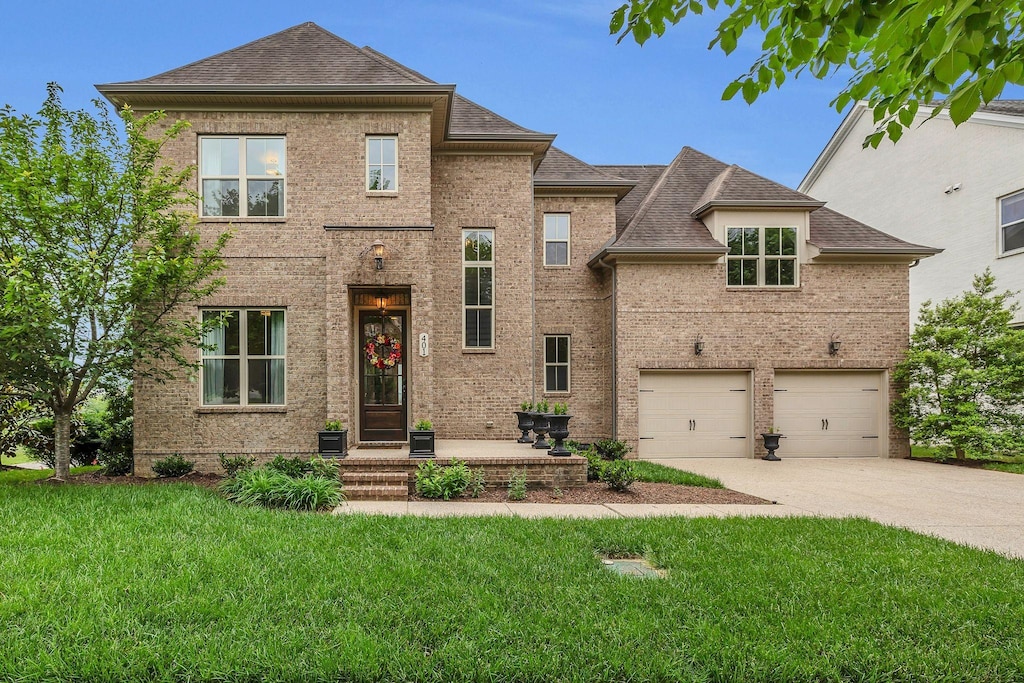 401 Cobert Ln, Franklin, TN 37064 - view of front of house with driveway, a front yard, brick siding, an attached garage, and a shingled roof