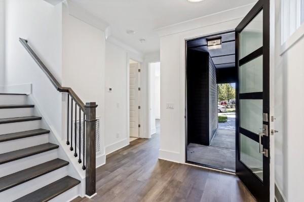 entryway with wood finished floors, stairway, baseboards, and crown molding