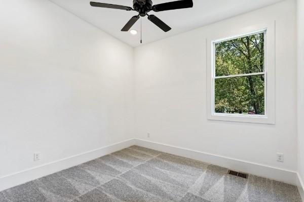 carpeted spare room with baseboards and a ceiling fan