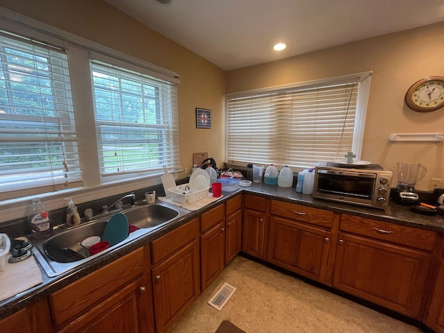 108 Butler Speedway, Bruceton, TN 38317 - kitchen with brown cabinets, a sink, dark countertops, and light colored carpet