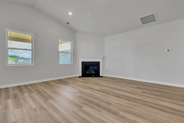 unfurnished living room featuring light wood-type flooring, vaulted ceiling, a fireplace with flush hearth, baseboards, and recessed lighting