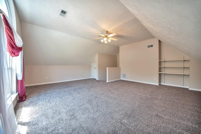 bonus room featuring lofted ceiling, a textured ceiling, ceiling fan, carpet, and baseboards