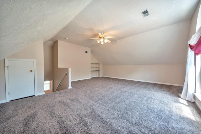 bonus room featuring carpet, lofted ceiling, a ceiling fan, baseboards, and a textured ceiling