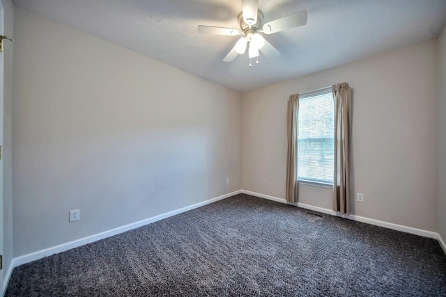 empty room with dark colored carpet, baseboards, and a ceiling fan