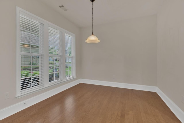 unfurnished dining area featuring dark wood-style flooring and baseboards