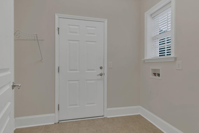 clothes washing area featuring hookup for a washing machine, light tile patterned floors, and baseboards