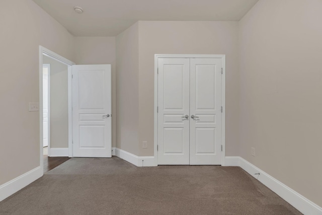 unfurnished bedroom featuring carpet, baseboards, and a closet