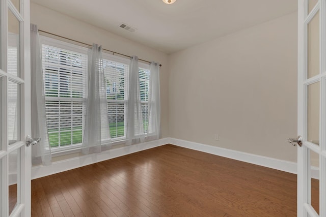 empty room with french doors, dark wood-type flooring, and baseboards