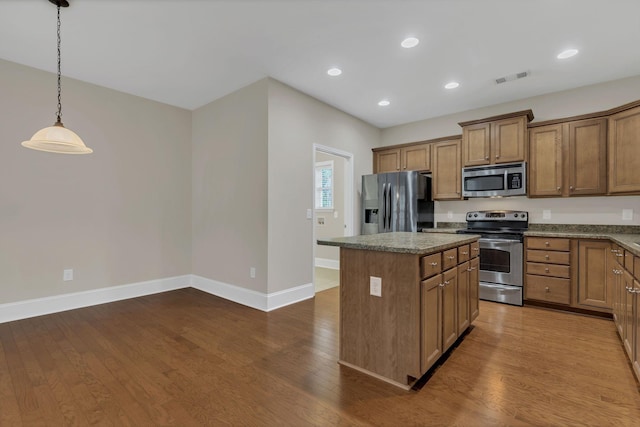 kitchen featuring appliances with stainless steel finishes, a center island, brown cabinets, baseboards, and recessed lighting