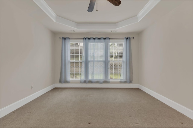 empty room featuring a raised ceiling, ornamental molding, carpet, ceiling fan, and baseboards