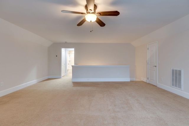 empty room featuring vaulted ceiling, light carpet, a ceiling fan, and baseboards