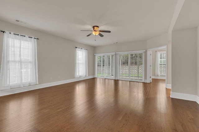 unfurnished living room with a ceiling fan, wood-type flooring, and baseboards