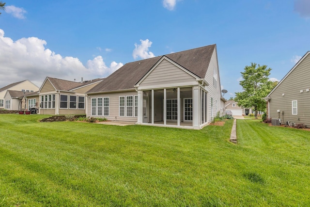back of house featuring a sunroom, a lawn, and roof with shingles