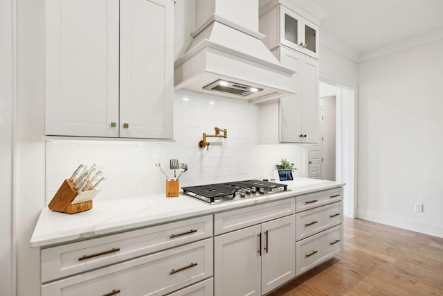 7214 Neills Branch Dr, College Grove, TN 37046 - kitchen featuring custom range hood, stainless steel gas cooktop, backsplash, baseboards, and light wood-style flooring