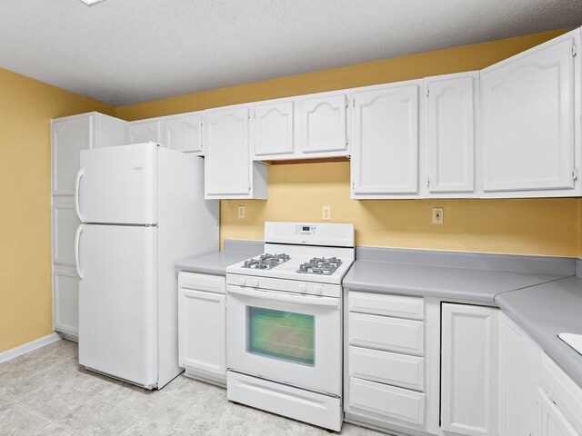 kitchen with white appliances, white cabinetry, and light countertops
