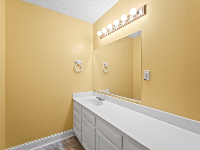 bathroom featuring baseboards, vanity, and a textured ceiling
