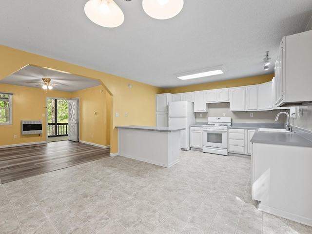 kitchen featuring white appliances, heating unit, a sink, open floor plan, and white cabinets