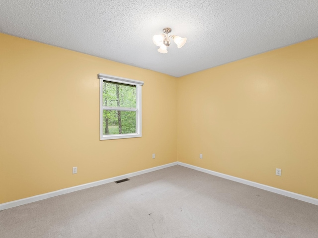 empty room with light carpet, baseboards, and a textured ceiling