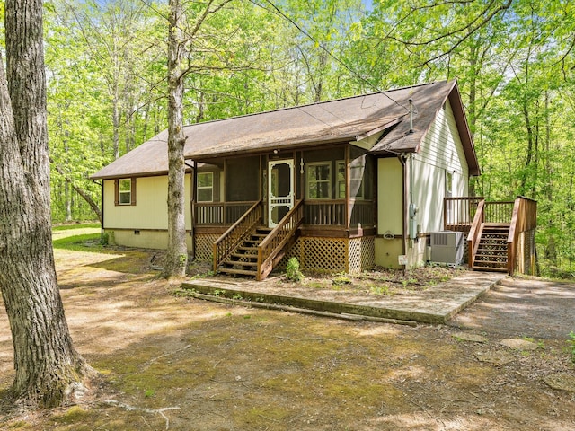 view of front of property featuring stairway, crawl space, central AC unit, a shingled roof, and a sunroom