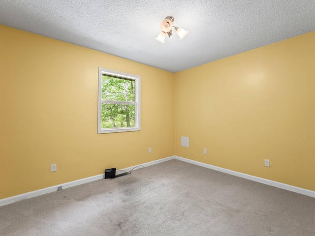 carpeted spare room with baseboards and a textured ceiling