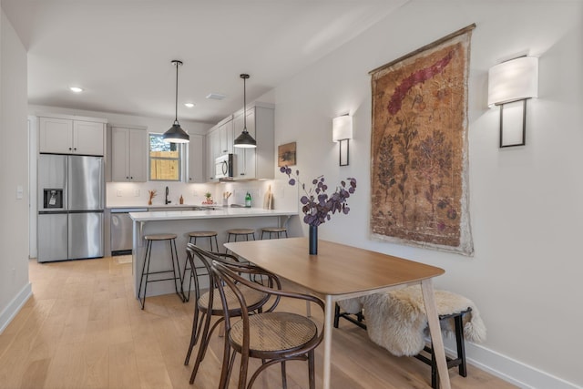 dining area featuring baseboards, light wood-style floors, and recessed lighting