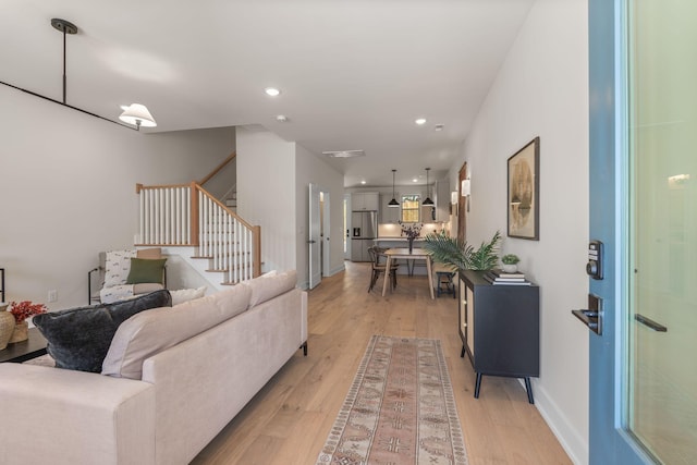 living area featuring stairs, light wood finished floors, recessed lighting, and baseboards