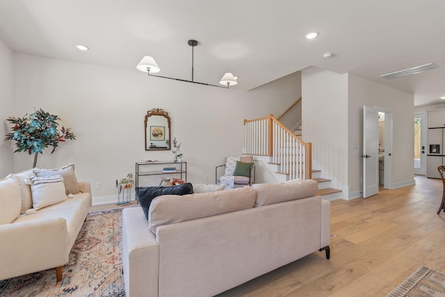 living room featuring light wood-type flooring, stairs, baseboards, and recessed lighting