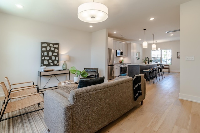 living room featuring baseboards, light wood-style floors, and recessed lighting