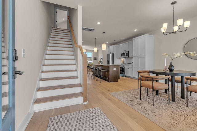 dining area with a chandelier, light wood-style floors, stairway, recessed lighting, and baseboards