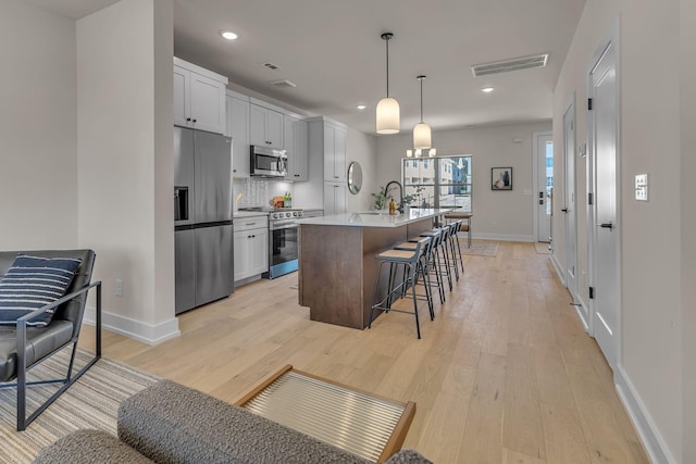 kitchen with stainless steel appliances, light wood-style floors, baseboards, a breakfast bar, and recessed lighting