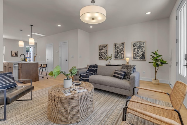 living area with light wood-type flooring, recessed lighting, and baseboards