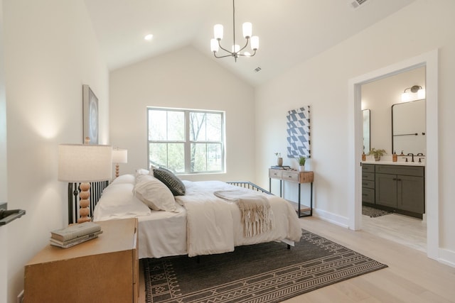 bedroom with light wood-style flooring, a chandelier, vaulted ceiling, ensuite bathroom, and a sink