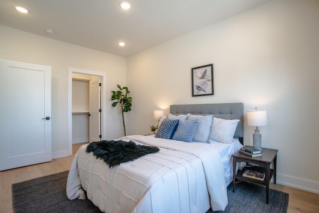 bedroom with wood finished floors, baseboards, recessed lighting, and a spacious closet