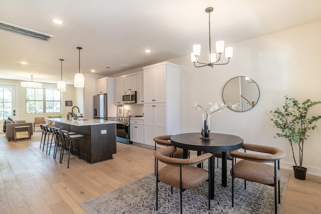 dining area with a chandelier, light wood-style flooring, recessed lighting, and baseboards