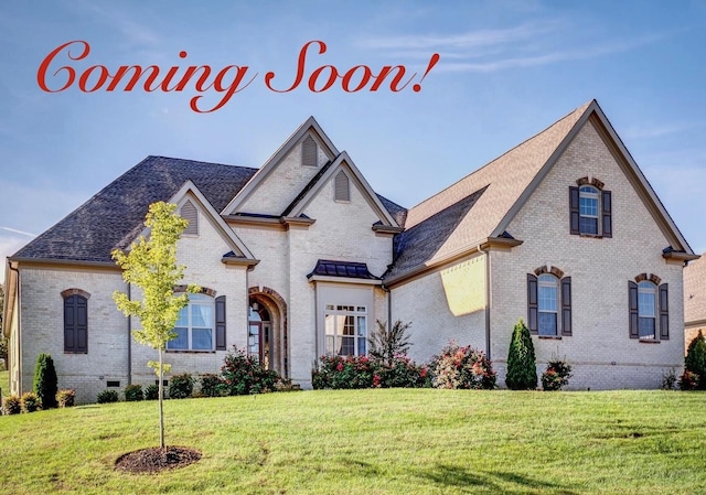 french country style house featuring brick siding, a front yard, crawl space, and roof with shingles