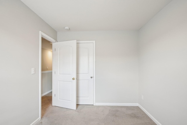 unfurnished bedroom featuring light carpet and baseboards