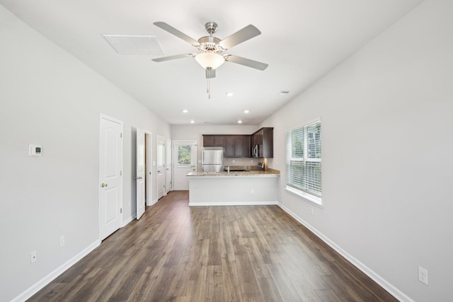 kitchen featuring appliances with stainless steel finishes, dark brown cabinetry, dark wood-type flooring, a peninsula, and a ceiling fan