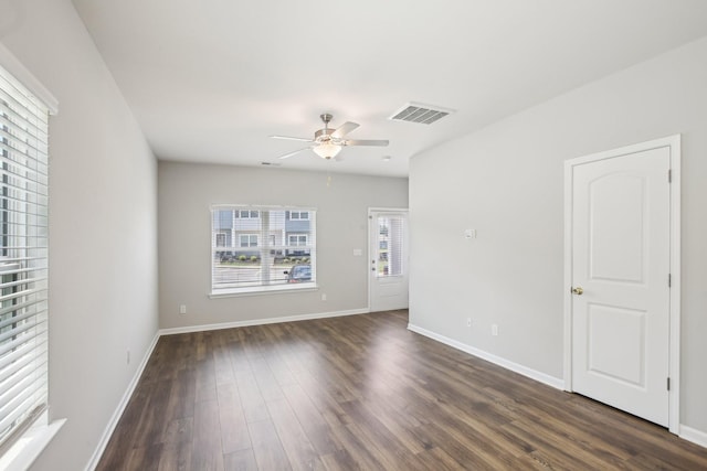 empty room featuring a ceiling fan, dark wood-type flooring, and baseboards