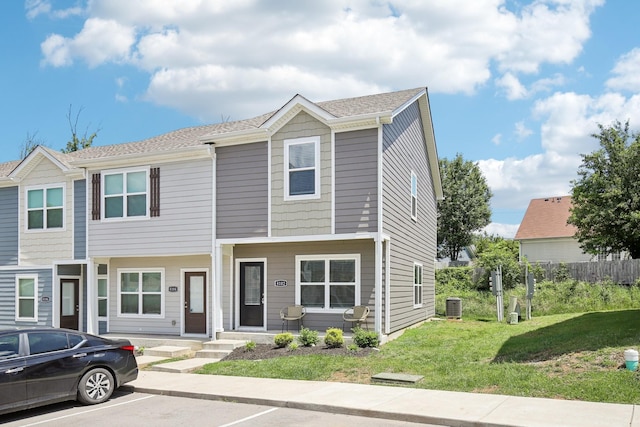 view of property with uncovered parking, a front lawn, and central air condition unit