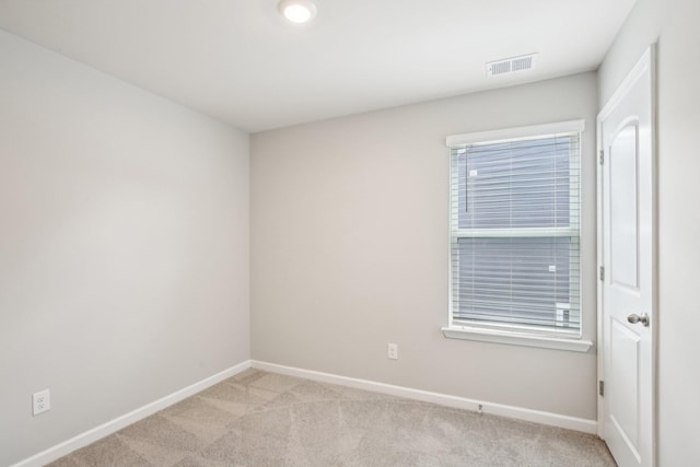 spare room with light colored carpet and baseboards