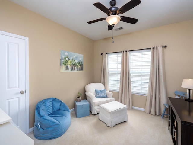 living area featuring light carpet, ceiling fan, and baseboards