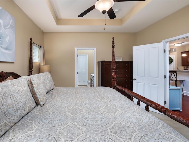 bedroom with a tray ceiling, carpet floors, and a ceiling fan