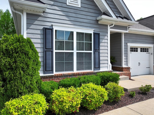 entrance to property featuring an attached garage and brick siding