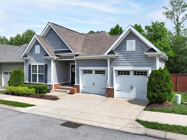 craftsman-style house featuring concrete driveway, a garage, a shingled roof, fence, and brick siding